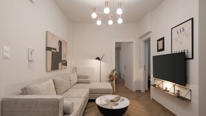 A modern living room with a sectional sofa, a round coffee table, a mounted TV, and a chandelier. - "Acropolis Kallisti" 2BR/2BA near Metro (Athina)