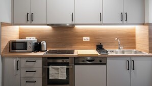 A modern kitchen with white cabinets, stainless steel appliances, and a wooden countertop. - "Acropolis Kallisti" 2BR/2BA near Metro (Athina)
