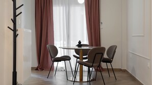 A dining area with a round table, four chairs, a hanging light fixture, and a radiator. - "Acropolis Kallisti" 2BR/2BA near Metro (Athina)