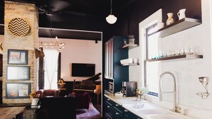 Moderni keittiö, jossa on suuri keittiösaareke, sisäänrakennettu uuni sekä hana, jossa on pesuallas. Keittiössä on myös ruokailutila, jossa on piano ja seinälle asennettu televisio.
