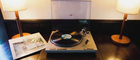 Un tocadiscos con un disco de vinilo, un cuadro enmarcado y dos lámparas sobre una mesa de madera.