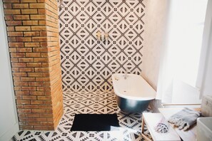 Bathroom features a geometric patterned tile design, a wall-mounted toilet, and a small rug.