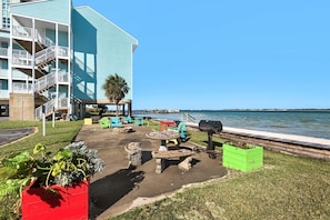 A waterfront patio with outdoor seating, a barbecue grill, and a view of the water. - Baywatch G5 (Pensacola Beach)