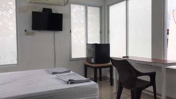 Simple, functional room with a single bed, TV, and chair.