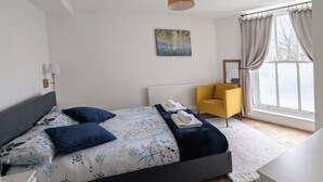 A bedroom with a bed, a chair, a radiator, and a window. - Stylish & Spacious 1 bed flat next to station (London)