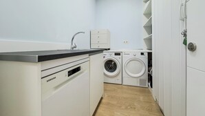 Ein Waschraum mit einer Samsung Waschmaschine, einem Trockner und einem Waschbecken.