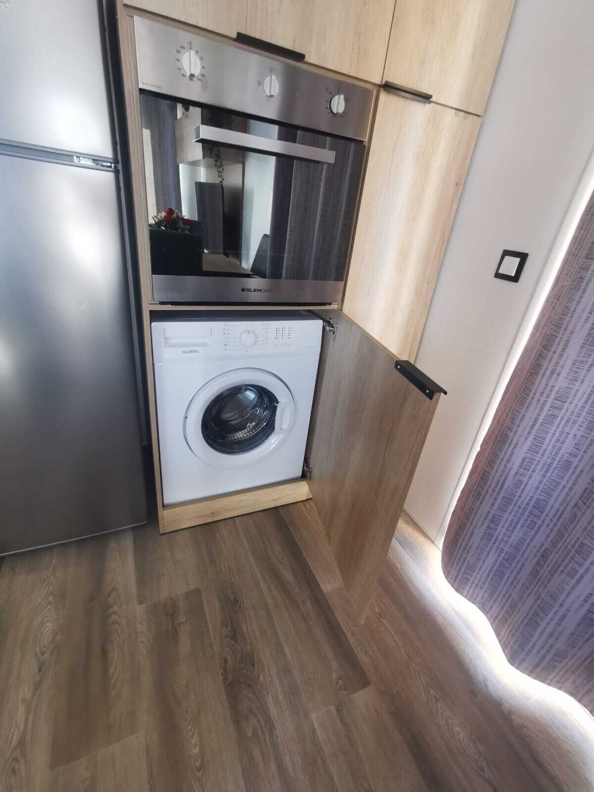 A compact kitchen with a built-in oven and a front-loading washing machine.