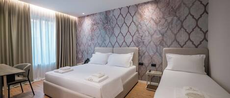 Une chambre d’hôtel avec deux lits, un bureau et une chaise.