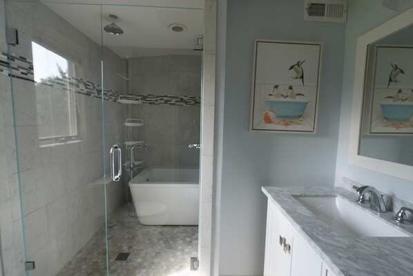 A modern bathroom with a glass-enclosed shower, a freestanding bathtub, and a marble vanity.