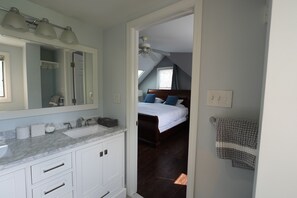 Une salle de bain avec un lavabo en marbre, des meubles blancs et un grand miroir.