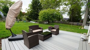 Een terras buiten met rieten meubilair, een overdekte parasol en een kleine tafel.
