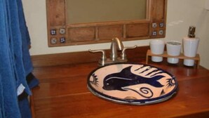 Un baño con tocador de madera, un lavamanos redondo con diseño de delfín y un espejo con marco de madera.