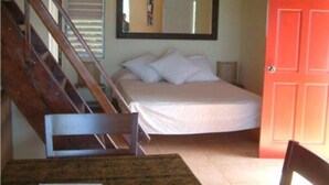 Un dormitorio con cama, una silla, una mesa, un espejo y una puerta roja.