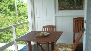 Una terraza de madera con una mesa, sillas, una puerta y un cuadro.