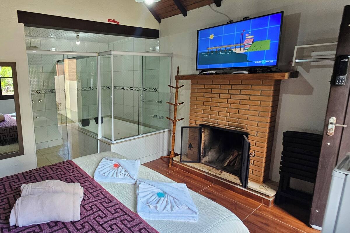 Une chambre d’hôtel équipée d’un lit, d’une douche en verre, d’une cheminée et d’un téléviseur.