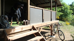 A wooden deck with a bench, a bicycle, and a dog statue. - Camping de l'Aigle (Aiguines)
