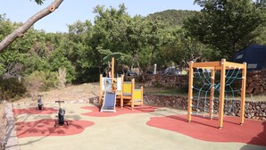 A playground with a slide, swings, and a climbing structure. - Camping de l'Aigle (Aiguines)