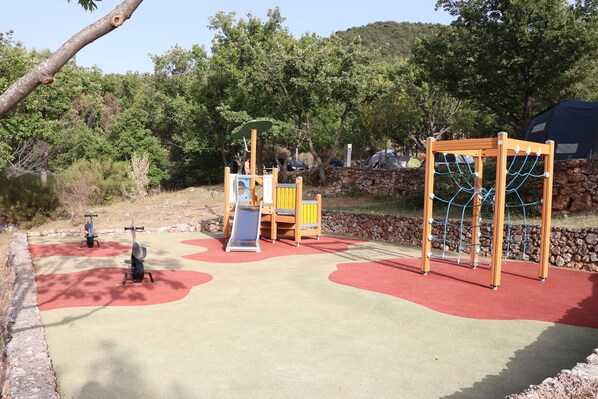 A playground with a slide, swings, and a climbing structure. - Camping de l'Aigle (Aiguines)