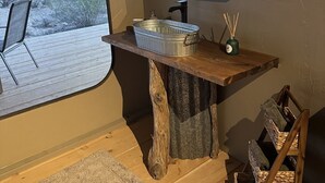 A bathroom with a rustic wooden vanity, a large window with a view of a snowy landscape, a small sink, and a mirror. - SaguaroGlamp (Marana)