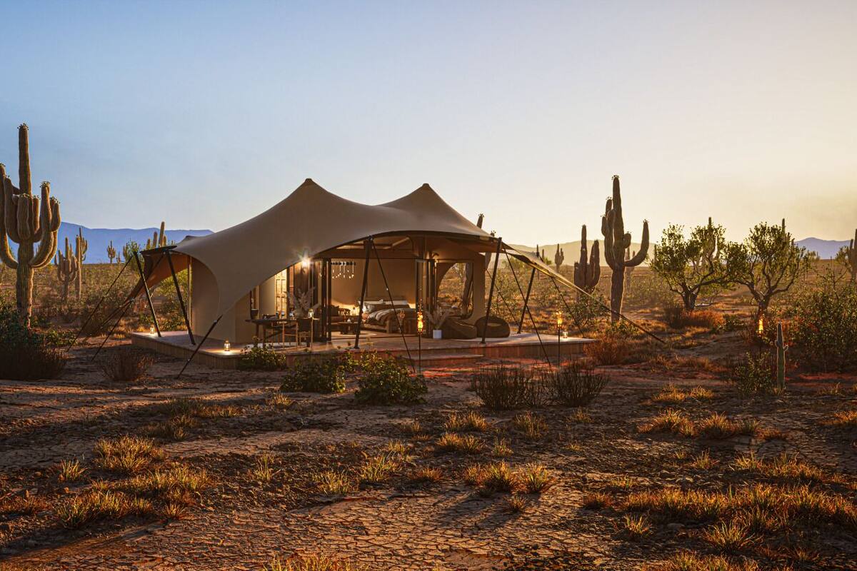 A desert tent-style accommodation with a central seating area and a view of the surrounding desert landscape.