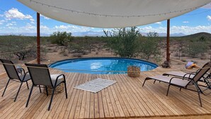 A wooden deck with a pool, lounge chairs, and a shaded area. - SaguaroGlamp (Marana)