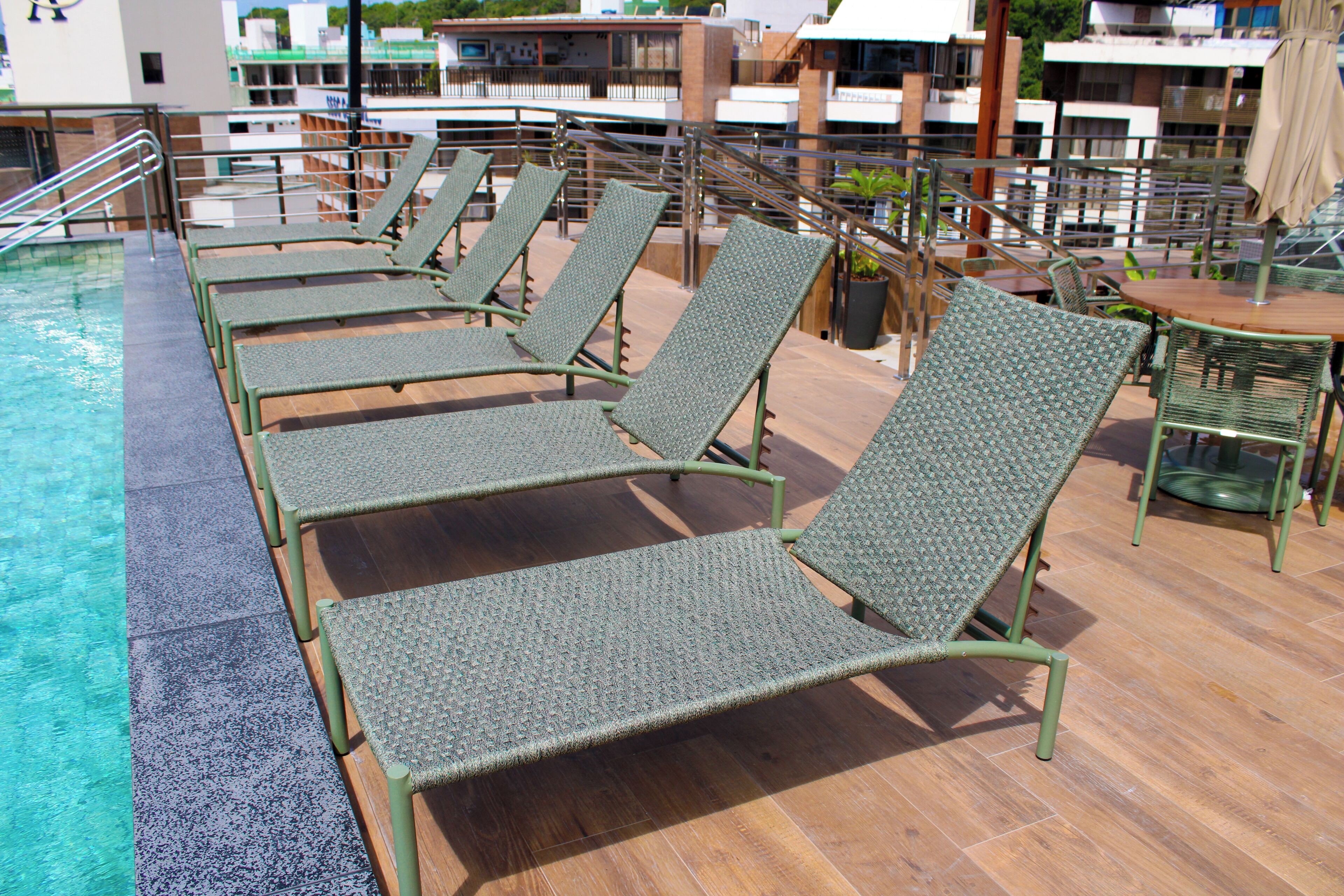 A rooftop pool area with lounge chairs and tables.