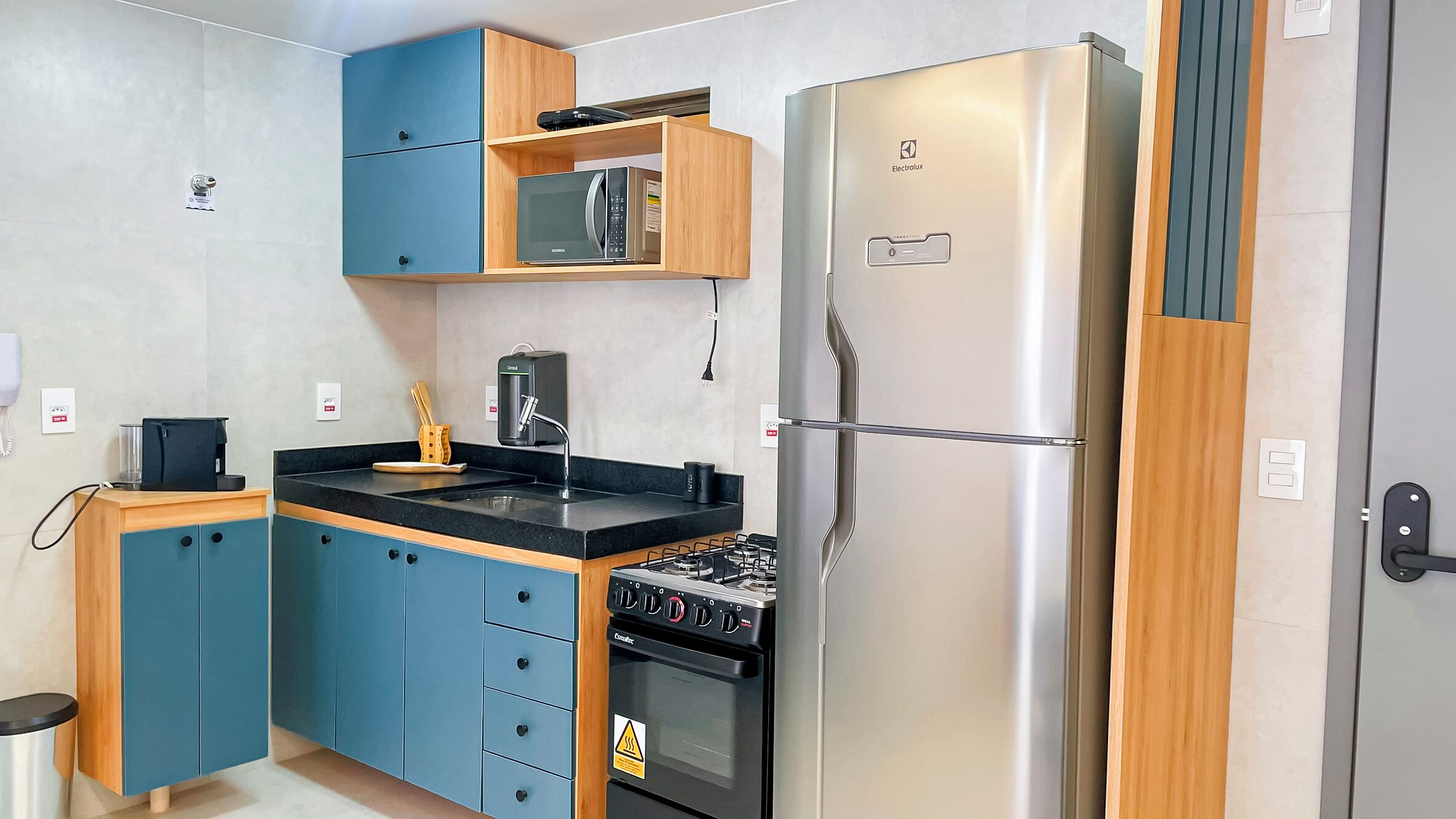Een kleine keuken met een magnetron, fornuis en koelkast.
