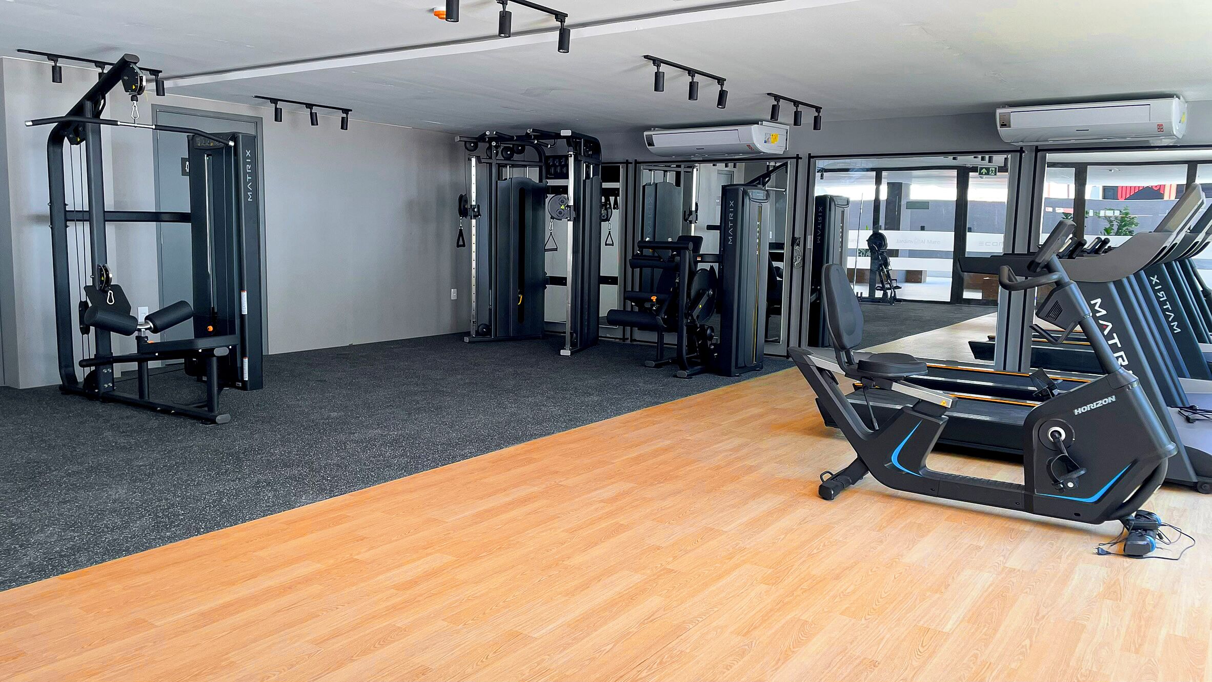 Une salle de sport équipée de matériel d’exercice, d’un tapis de course et dotée d’un plancher en bois.