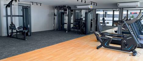 Une salle de sport équipée de matériel d’exercice, d’un tapis de course et dotée d’un plancher en bois.