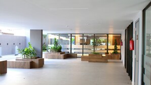 Un vestíbulo amplio con ventanas grandes, mobiliario moderno y plantas de interior.