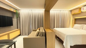 Ett modernt hotellrum med en stor säng, en soffa, en platt-TV och en vägg med träpanel som ger rummet en speciell karaktär.