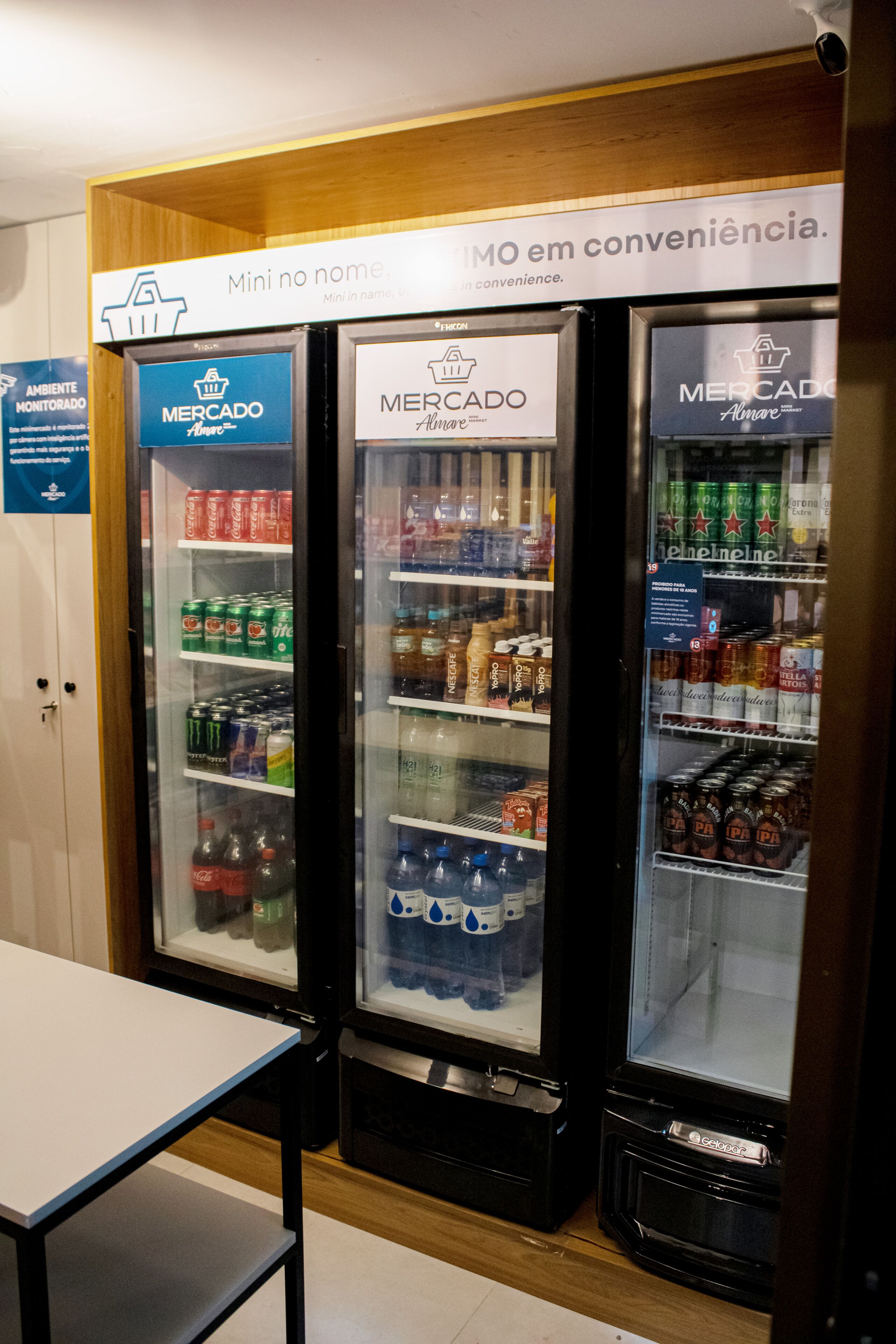 Tres dispensadores refrigerados para bebidas con la etiqueta 'Mercado' y diferentes bebidas en su interior.