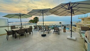 Une terrasse sur le toit, avec des sièges en plein air, des parasols et une vue sur la mer.