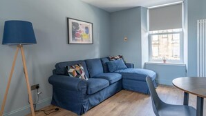 A modern living room with a blue sofa, a small round table, and a lamp.