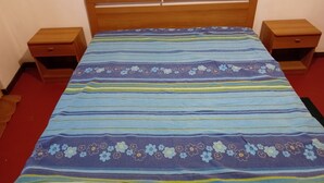 Ein Bett mit gestreifter Bettdecke, zwei Nachttische aus Holz und ein roter Teppich.