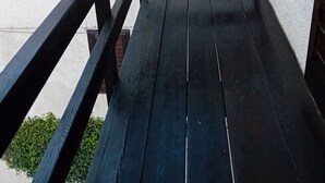 Eine hölzerne Bank mit Metallgeländern vor einer weißen Wand.