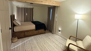 A bedroom with a bed, a chair, a lamp, and a patterned rug. - Enchanting whole home on Nancy lake with WiFi in Willow Alaska! (Willow)