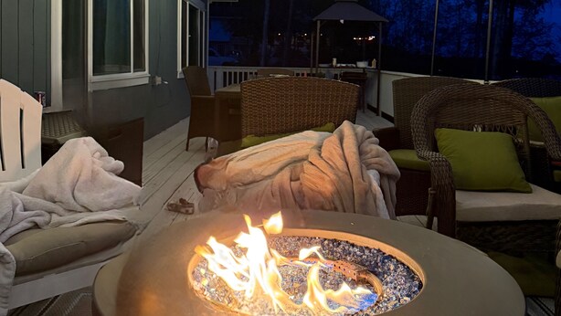An outdoor patio with a fire pit, string lights, and wicker furniture. - Enchanting whole home on Nancy lake with WiFi in Willow Alaska! (Willow)