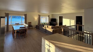 A spacious living area with a dining table, sofa, and a view of the outdoors. - Enchanting whole home on Nancy lake with WiFi in Willow Alaska! (Willow)