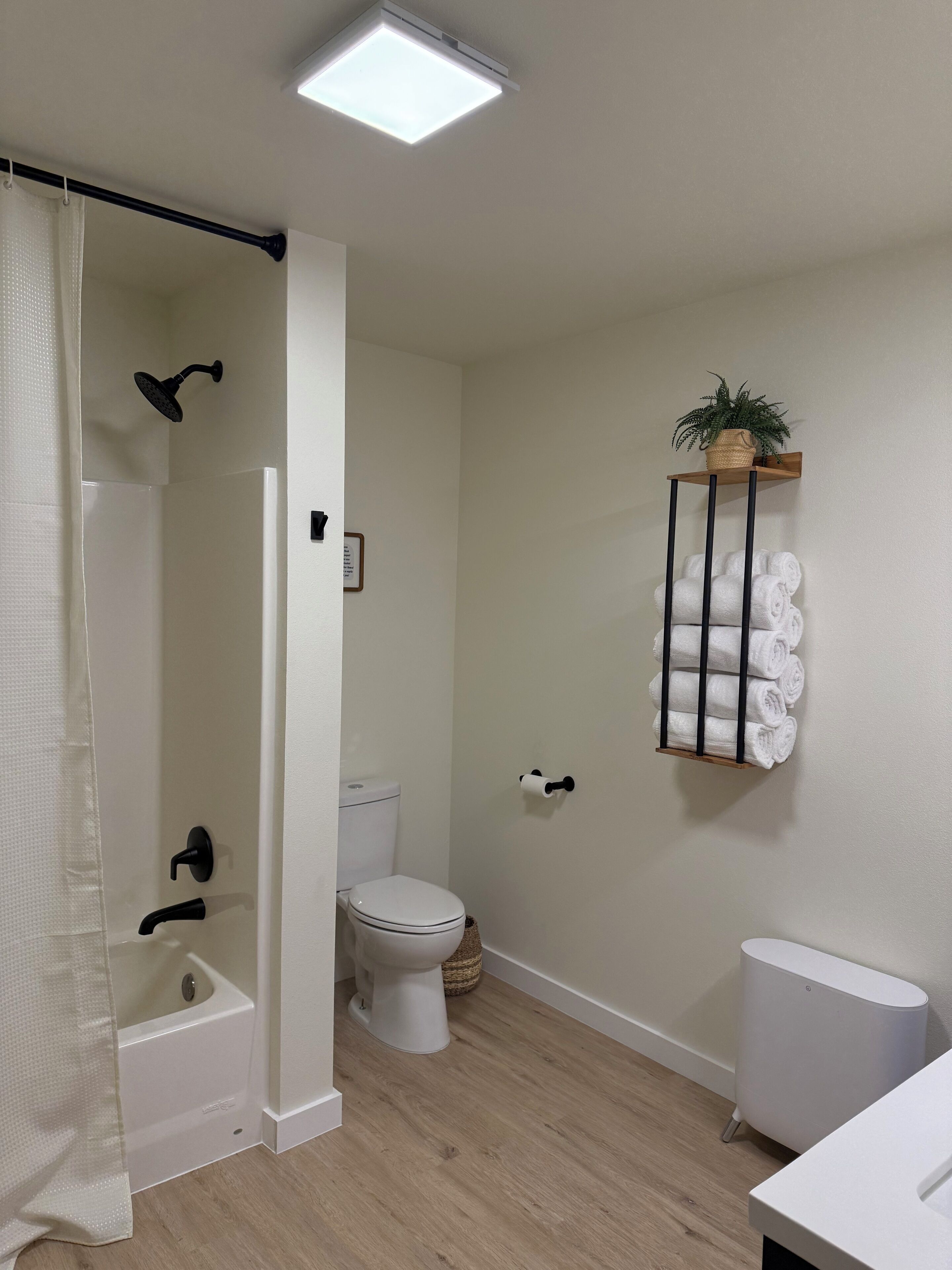 A bathroom with a shower, toilet, and a towel rack.