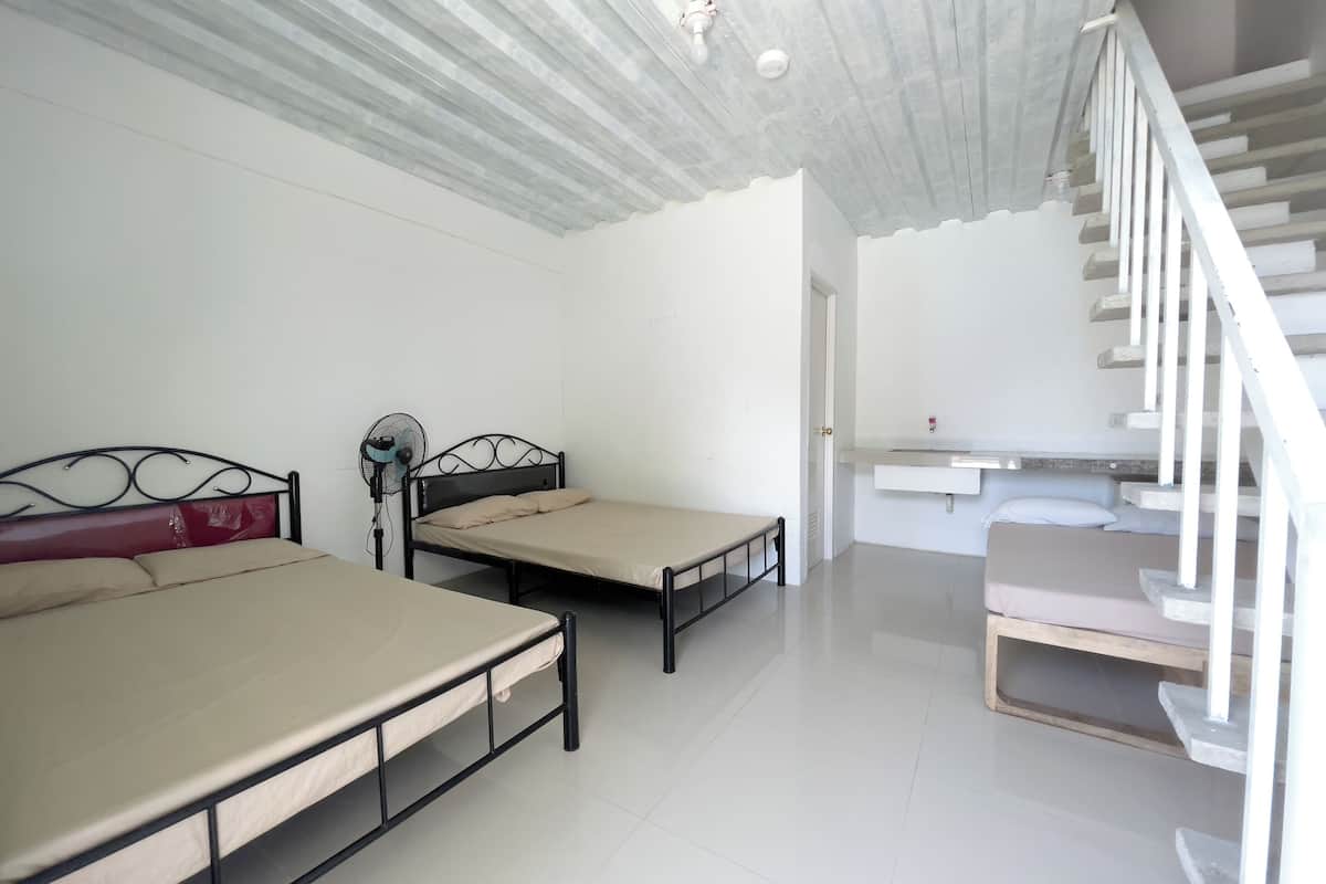 A bedroom with two beds, a staircase, and a white ceiling.