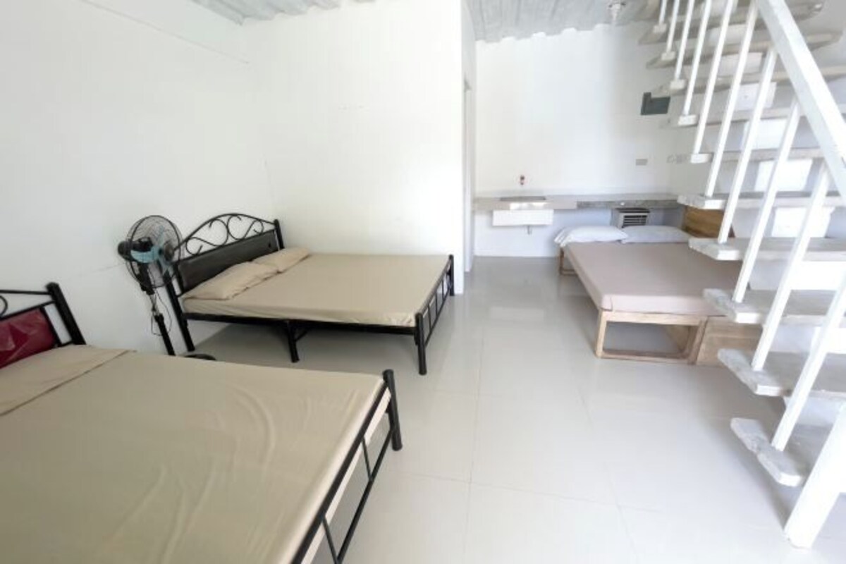 Ein Zimmer mit zwei Betten, einem kleinen Tisch und einer weißen Treppe.