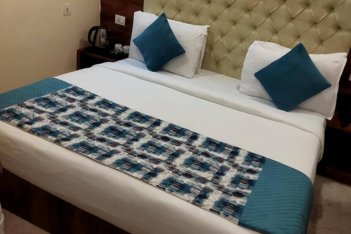 Un lit bien fait, avec une couvre-lit à motifs, deux oreillers et une tête de lit capitonnée.