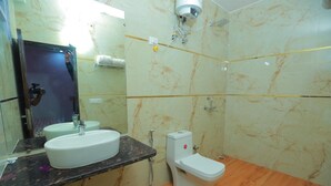 Een badkamer met een marmeren wand, een wastafel, toilet en spiegel.