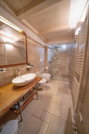 A modern bathroom with a wooden vanity, a large mirror, a sink, a toilet, and a glass-enclosed shower area.