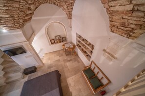 A room with stone walls, a wooden chair, a small table, and a bed. - Holiday Home   Casa Sara (Martina Franca)