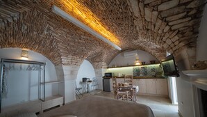 Een slaapkamer met een groot bed, een bureau en een kitchenette, gelegen in een kamer met een gewelfd stenen plafond.