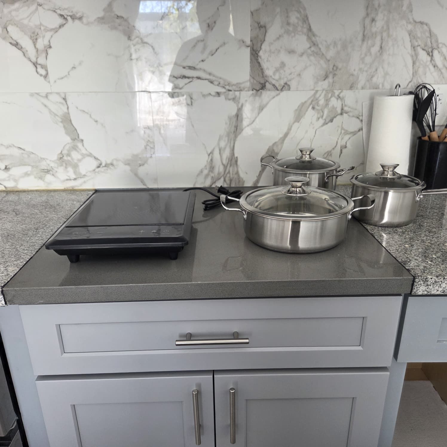 A kitchen with marble backsplash, stainless steel pots, and a built-in oven.