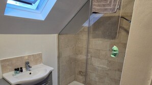 Une salle de bain avec une douche à parois de verre, un lavabo et une fenêtre située au-dessus du lavabo.