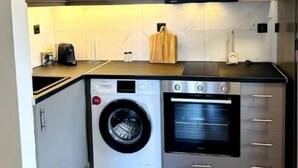 A compact kitchen with grey cabinets, a washing machine, and an oven.